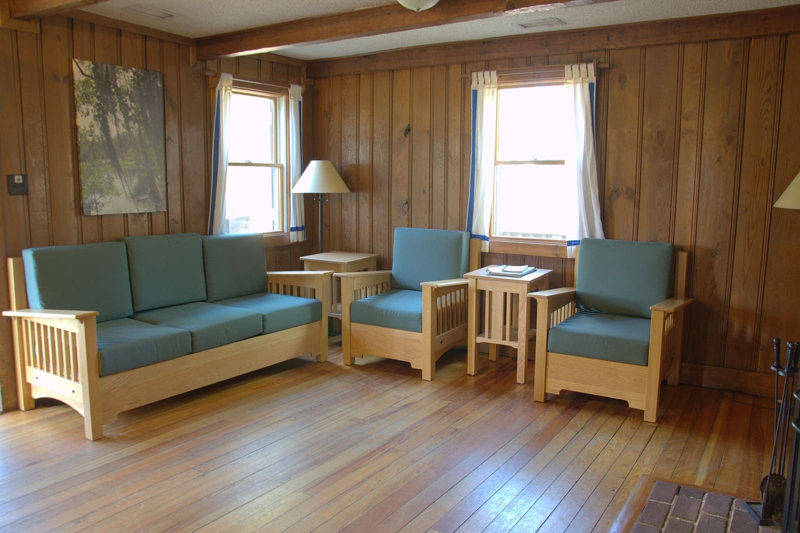 Wood-panelled cabin living room with a sofa, two armchairs and hardwood floor