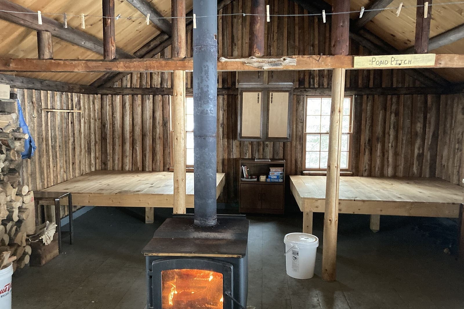 Black wood stove with a fire burning inside a rustic log cabin