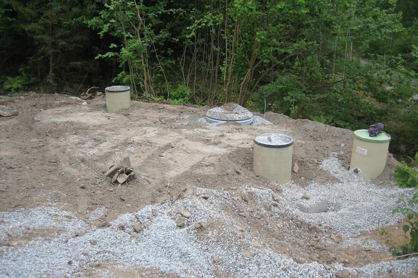 Newly installed septic tank risers and lids in freshly graded soil and gravel